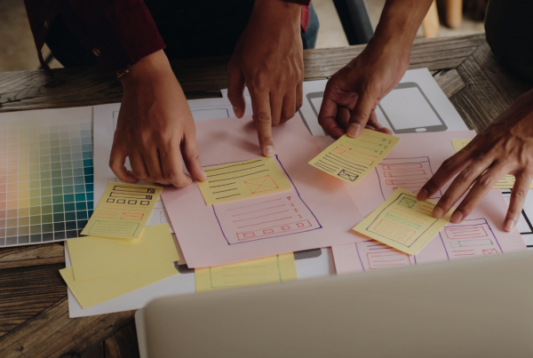 Two pairs of hands moving around papers on a table, representing "rapid prototyping" as an idea.