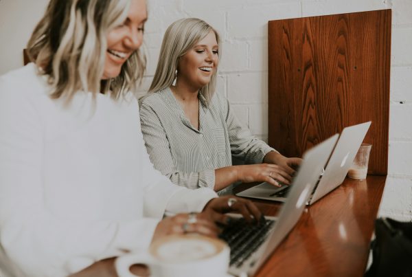 Two women with laptops coding with low-code/no-code tools