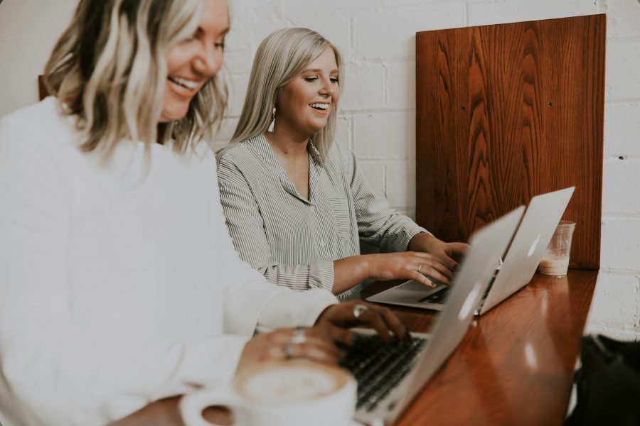 Two women with laptops coding with low-code/no-code tools
