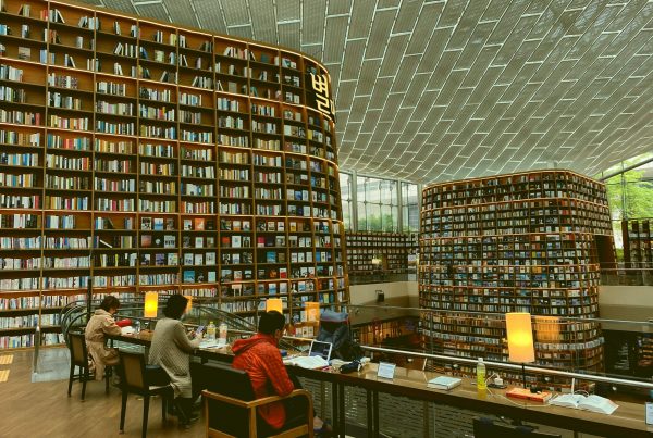 A modern library using a relational database to stay organized, with bookshelves that reach the ceiling. At the bottom, there are people sat at desks using their laptops.