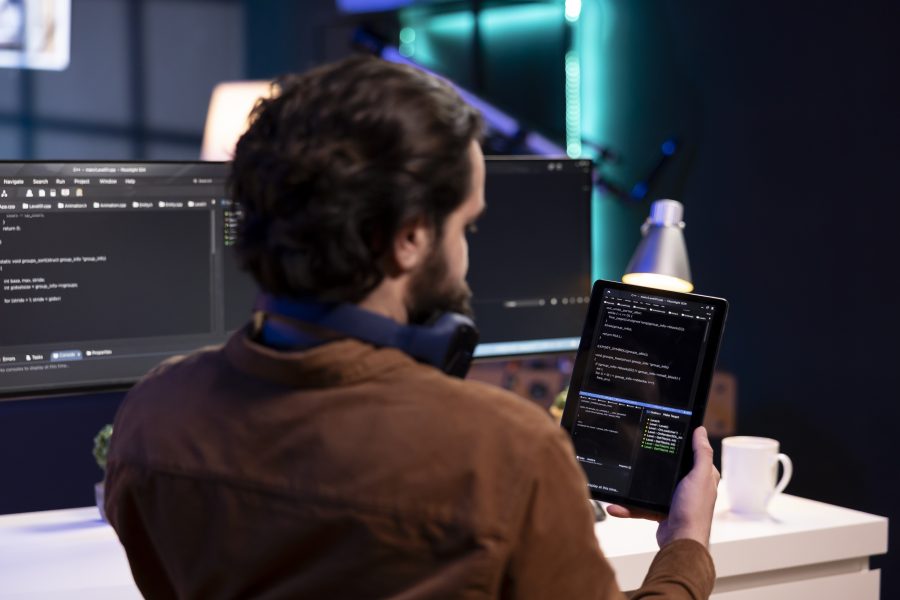 Man learning how to develop an app in front of his desk and holding a tablet.